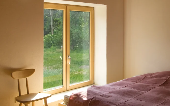 La chambre à coucher, enduite d'un crépi d'argile Baumit, est chaleureuse et réduite à l'essentiel.