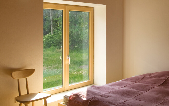 La chambre à coucher, enduite d'un crépi d'argile Baumit, est chaleureuse et réduite à l'essentiel.