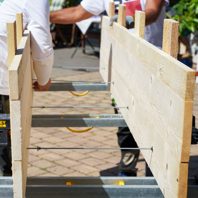 Die Schaltafeln für das Schalungselement werden mit den Gewindestangen verbunden und von außen verschraubt. Diese Arbeit wird mit zwei Personen ausgeführt und ist damit eine Erleichterung.